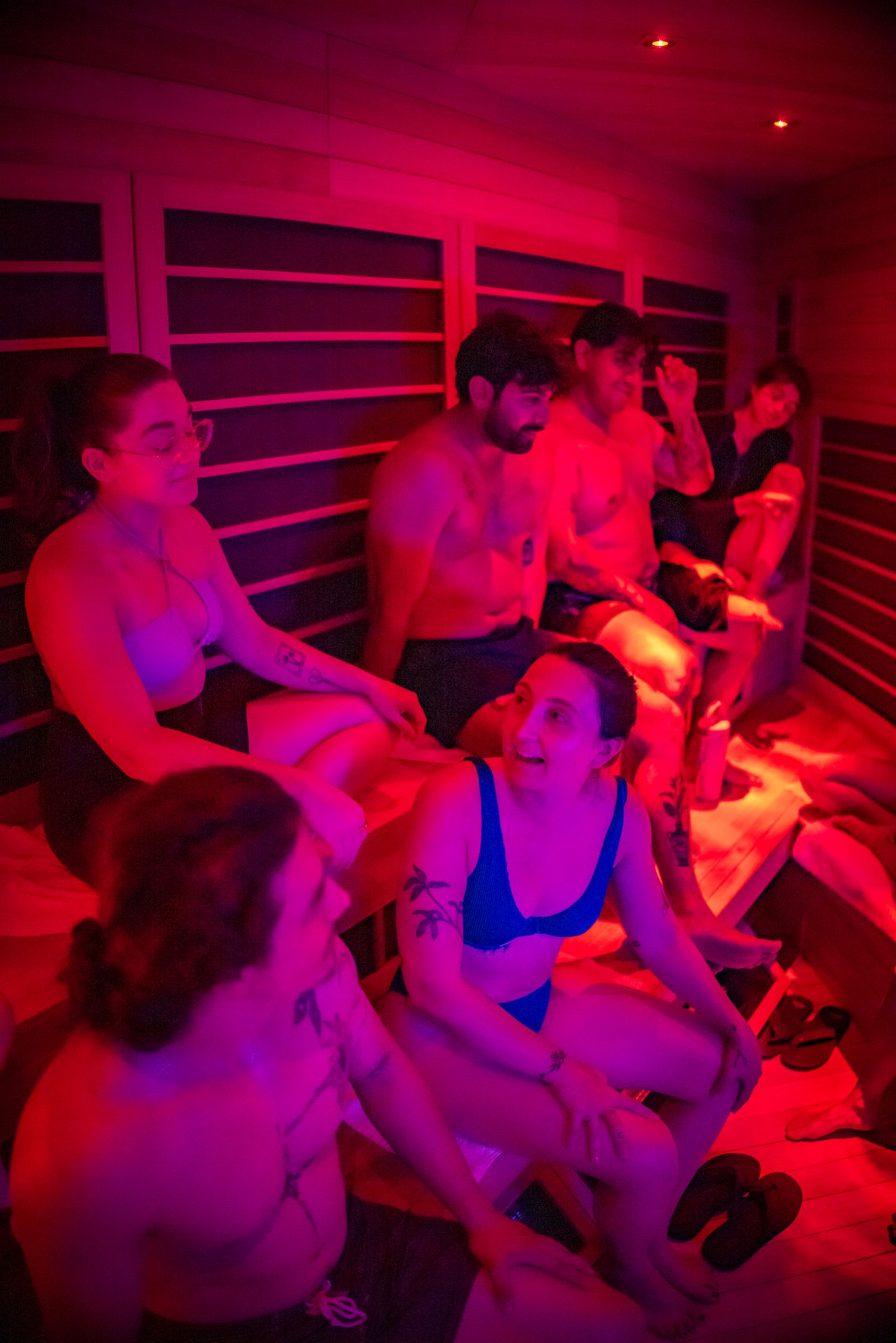 Group infrared sauna session under red light at Cellevate wellness spa — lifestyle brand photography for a Temecula Valley wellness studio