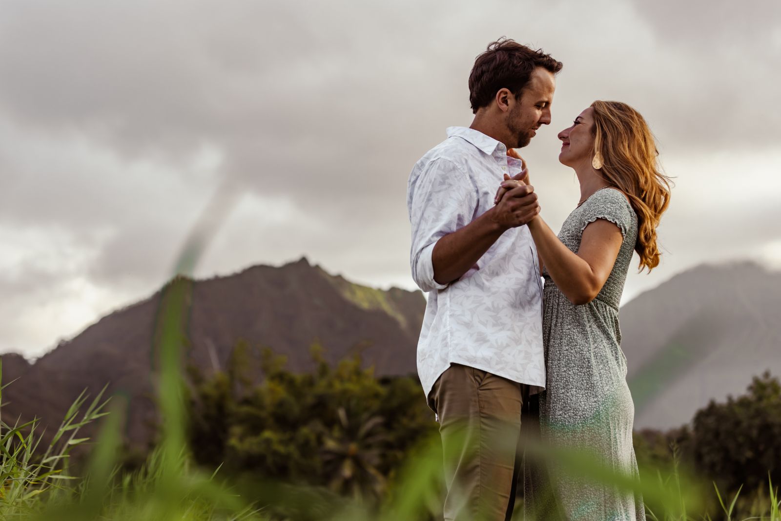 Couple dancing in a green field with Hawaiian mountains behind them — wedding and engagement photography by Murrieta Media, serving Murrieta, Temecula and Southern California