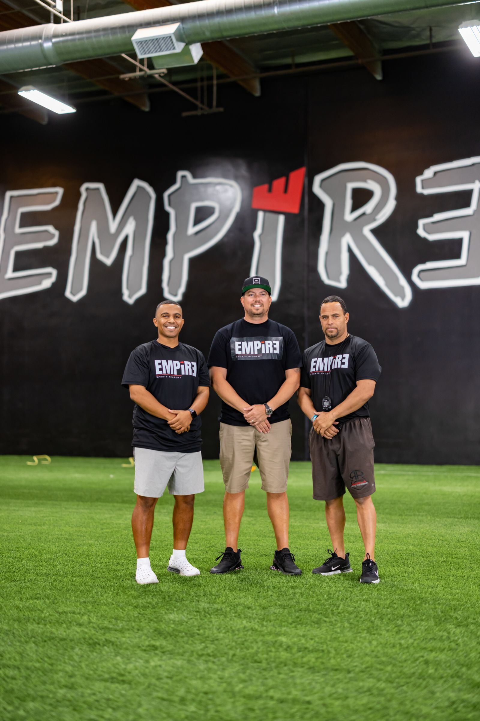 Empire Sports Academy coaches on the indoor turf field in front of the Empire wall — team photography by Murrieta Media